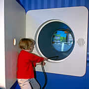 Exposition Electricité - Un enfant tire sur le câble électrique du jeu interactif : qu'y-a-t-il derrière la prise ?