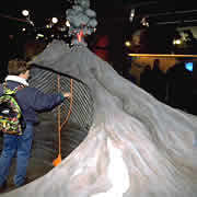 Exposition Roches et volcans - Un enfant observe la maquette d'un volcan en éruption